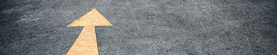 Yellow arrow pointing forward on black pavement