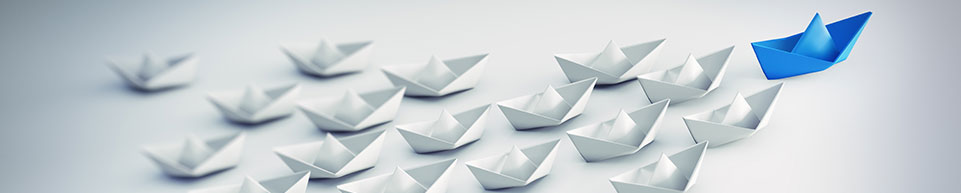 Paper boats in formation with one blue boat leading the way